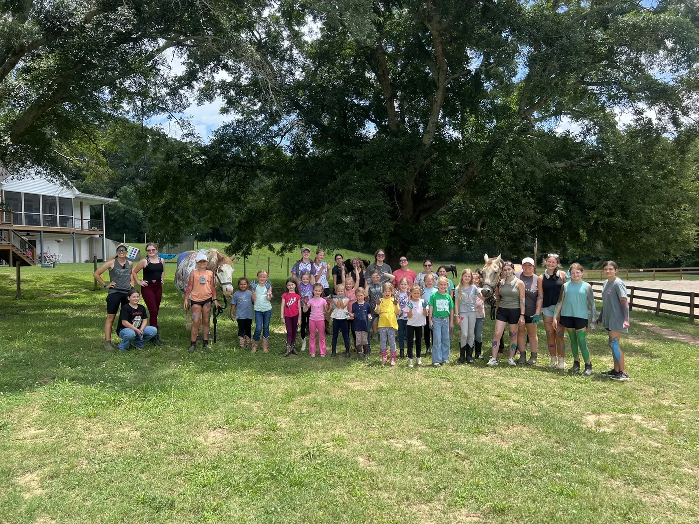 The whole June 22 to 24 camp group with two horses under the oak at Horses and Hope
